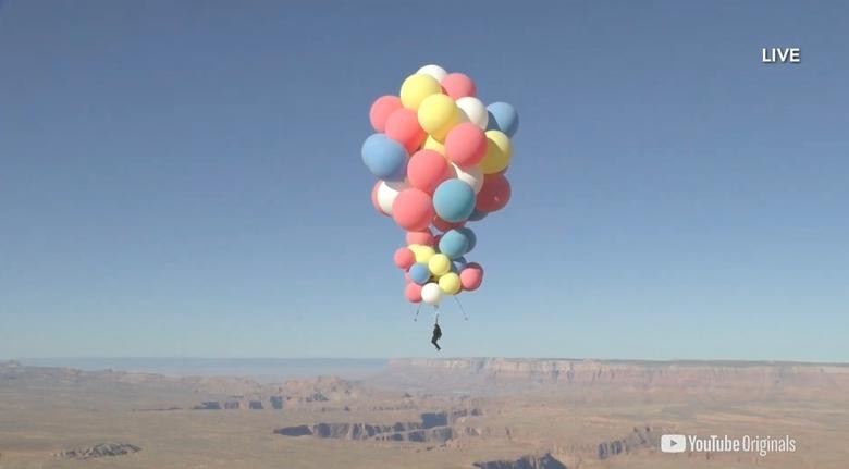 Extreme performer David Blaine hangs with a parachute under a cluster of balloons during a stunt to fly thousands of feet into the air over Page, Arizona. David Blaine/via REUTERS